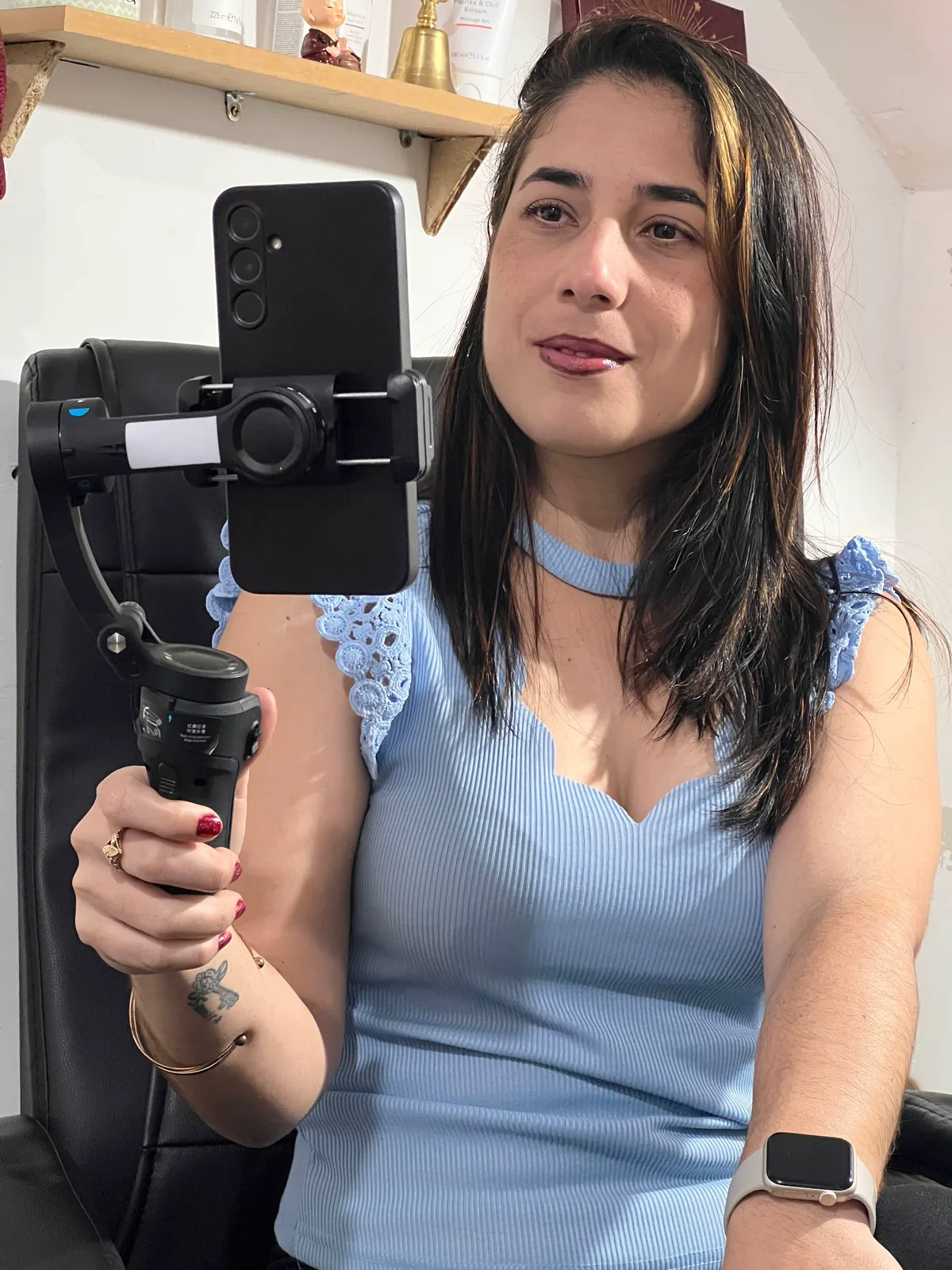 Susana sosteniendo un estabilizador con el celular sujeto, lista para grabar